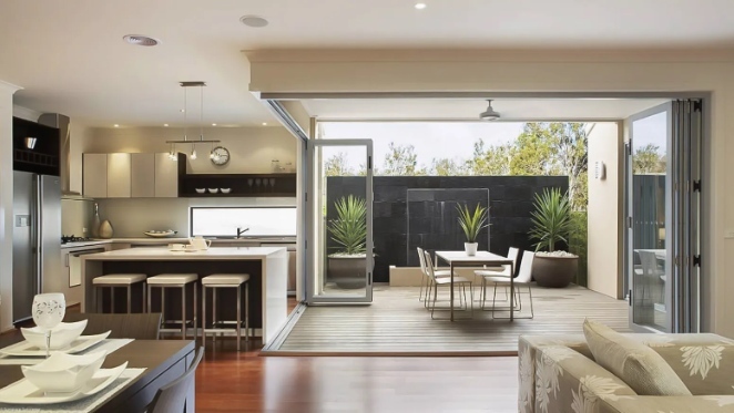 Salon donnant sur petit patio de jardin avec fenêtres pliantes WeatherMaster de chez Sunspace Québec - Sunspace Sunrooms